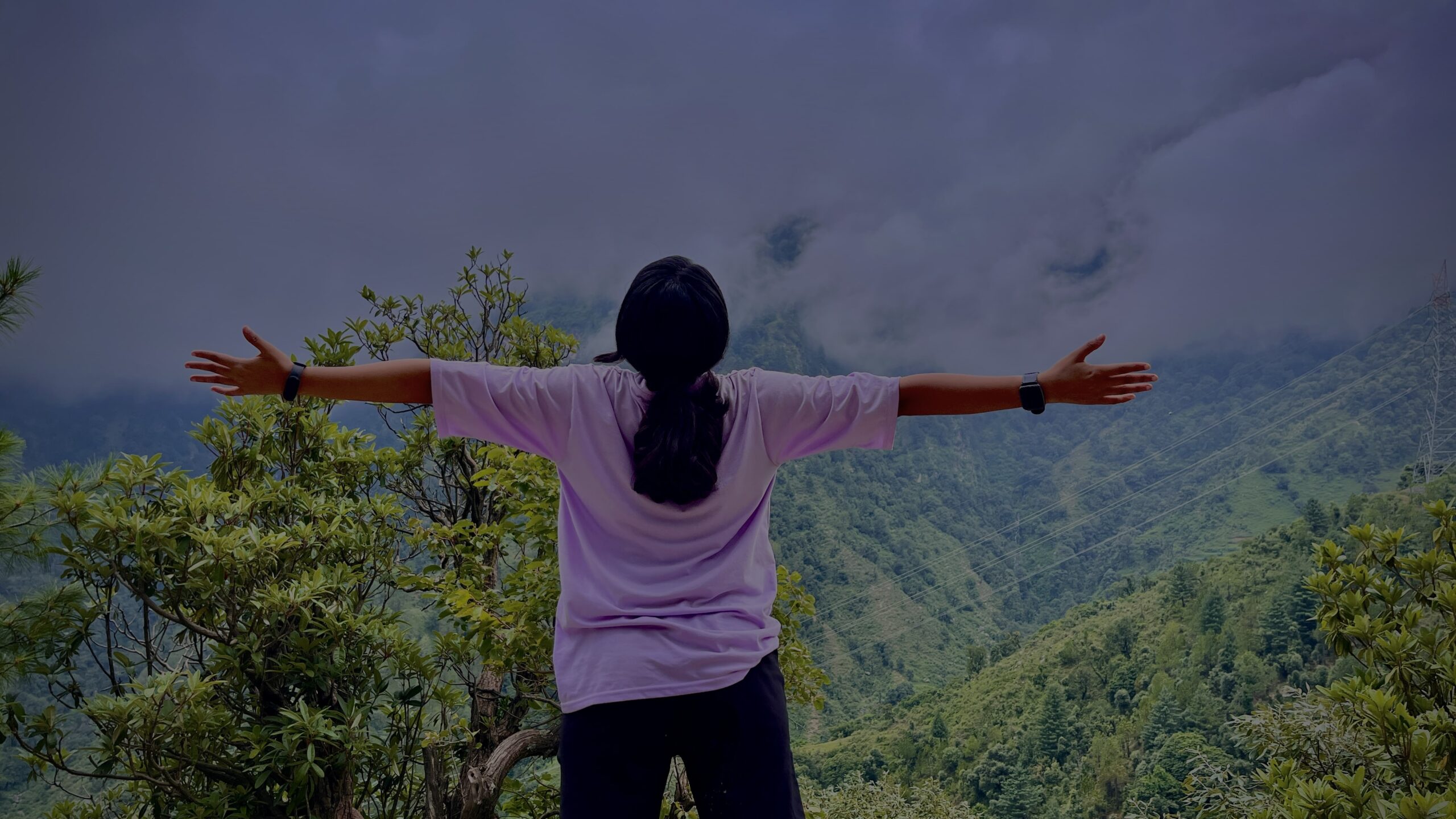 Image of a person standing with open arms in front of a mountain.